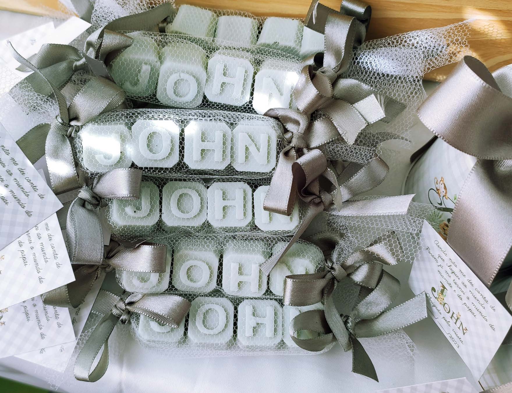 Sabonetinhos artesanais formando o nome John, com laços e embalagens personalizadas
